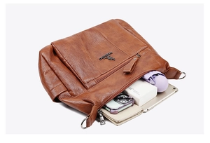 Internal storage detail of brown leather crossbody bag showing large capacity and compartments