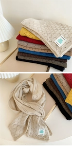 Close-up of multicolored knitted scarves featuring hollow diamond patterns and fashion labels