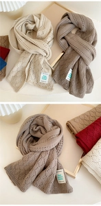 Close-up of diamond-pattern knit scarf with a woven label on soft beige background