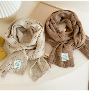 Detailed macro view of hollow-out diamond knit pattern on soft winter scarves in beige and brown