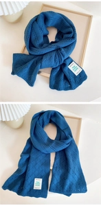 Detail of teal blue knitted scarf featuring intricate hollow patterns and premium fabric