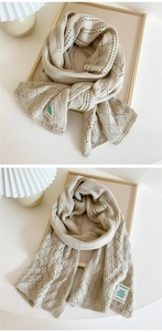 Macro detail of soft knit scarf featuring delicate openwork pattern and woven label