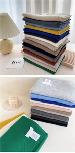 Macro view of multi-color knitted scarves showing detailed fine stitch texture and fabric label