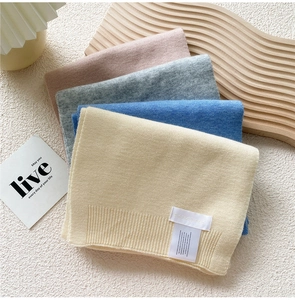 Close-up of colorful knitted winter scarves with ribbed edges and minimalist woven labels