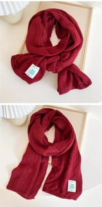 Detail of burgundy knit scarf with hollow wave texture and woven brand label