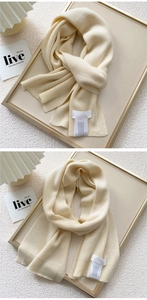 Detail of cream white knit scarf featuring soft vertical ribbing and woven label texture