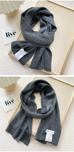 Detail of dark grey knitted scarf with white fabric care label and wool texture