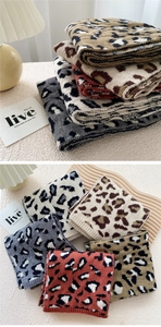 Detail of leopard jacquard knit scarves in brown and beige tones with thick soft texture
