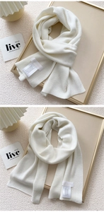 Macro detail of creamy white knitted scarf showing fine vertical ribbing and wash label