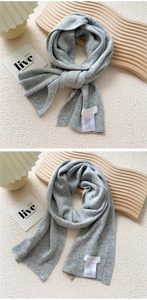 Detail of grey knitted scarf showing fine vertical rib texture and ribbed edge finish