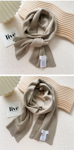 Detail shot of beige knitted scarf texture showing fine ribbing and wash care label