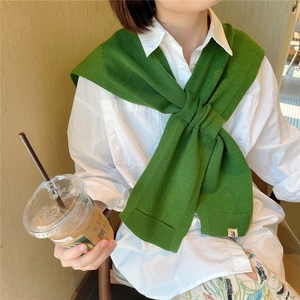 Green knitted shawl scarf with minimalist woven texture and letter patch over white shirt