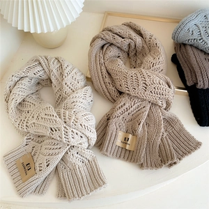 Thick cable knit scarves in solid colors featuring elegant textures and brand label tags