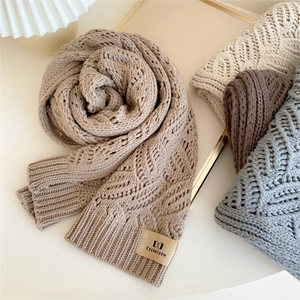 Thick khaki chunky knit scarf with leather label on a minimalist aesthetic background