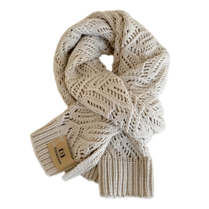 Thick cream cable knit winter scarf with premium leather brand label on white background