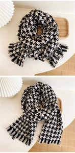 Detail of soft black and white houndstooth scarf with classic fringe and cozy knit texture