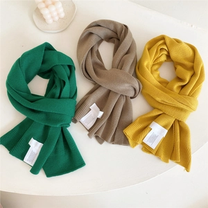 Three minimalist ribbed knit scarves in green, brown and yellow displayed on white background