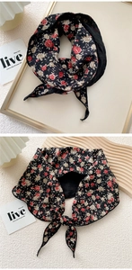 Detail of black floral silk scarf with small red flowers tied in an elegant bow knot