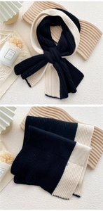 Detail of cross-knit scarf showing thick ribbed texture and black-and-white color block