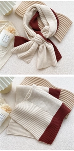 Detail of cream and wine red knit scarf featuring soft ribbed texture and color block design