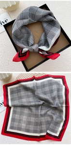 Detail of silk scarf showing houndstooth patterns and red striped border on wood tray
