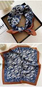 Detail of silk square scarf with paisley pattern and rust red border in a gift box