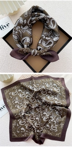 Detailed view of square silk scarf with white paisley pattern on dark coffee background