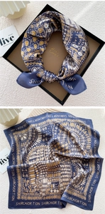 Detail of navy blue silk square scarf with gold geometric patterns in a luxury gift box