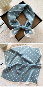 Macro detail of a blue polka dot silk scarf showing smooth texture and French style design