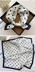 Detail of silk square scarf featuring black polka dots and border in a luxury gift box