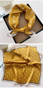 Detail of silk scarf showing yellow polka dot pattern and elegant contrast hem border