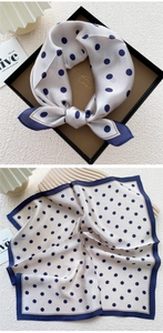 Macro shot of navy blue polka dot silk scarf with gold border detailing on silver silk