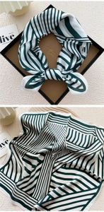 Detail view of dark green and white striped silk scarf tied in a bow in a gift box
