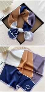 Close-up of silk square scarf featuring geometric color blocks and heart patterns