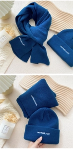 Detail of dark blue knit scarf and beanie set with white embroidery in gift display