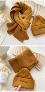 Detail of yellow knit scarf and beanie set with black embroidered normalcrush text