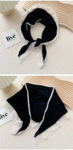 Detail of black cotton linen scarf with white lace trim and decorative mini pom-poms