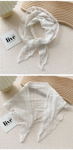Detail of white cotton linen triangle scarf with crochet floral lace and pom pom trim