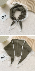 Close-up of olive green cotton linen scarf with white floral lace trim and pompom details