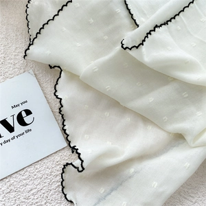 White linen triangle scarf with black wavy edges and textured polka dot jacquard pattern