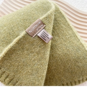 Detail of green knitted scarf showing fabric texture and material composition tag