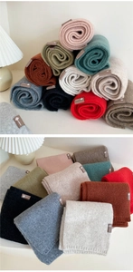 Close-up of colorful knitted scarves with woven labels on a white home setting