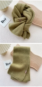 Detail of green knitted scarf showing ribbed texture and minimalist brand label
