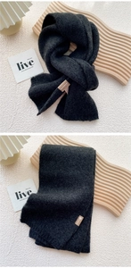Detail of dark grey knitted scarf showing soft texture and premium leather brand tag