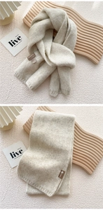 Close-up of oatmeal knit scarf texture and material tag showing soft thick plush weave