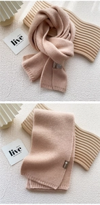 Close-up of pink knit scarf showing material tag and soft ribbed texture detail