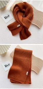 Close-up of caramel knitted scarf with ribbed edge and elegant decorative fabric label