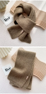 Detail of dark coffee knitted scarf featuring ribbed edges and a premium brand leather label