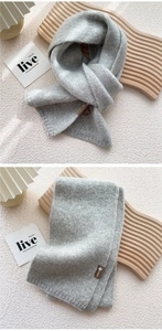 Detail of light gray knit scarf texture with stylish brown leather patch detail