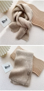 Detail of oatmeal knitted scarf featuring thick knit texture and brown decorative label